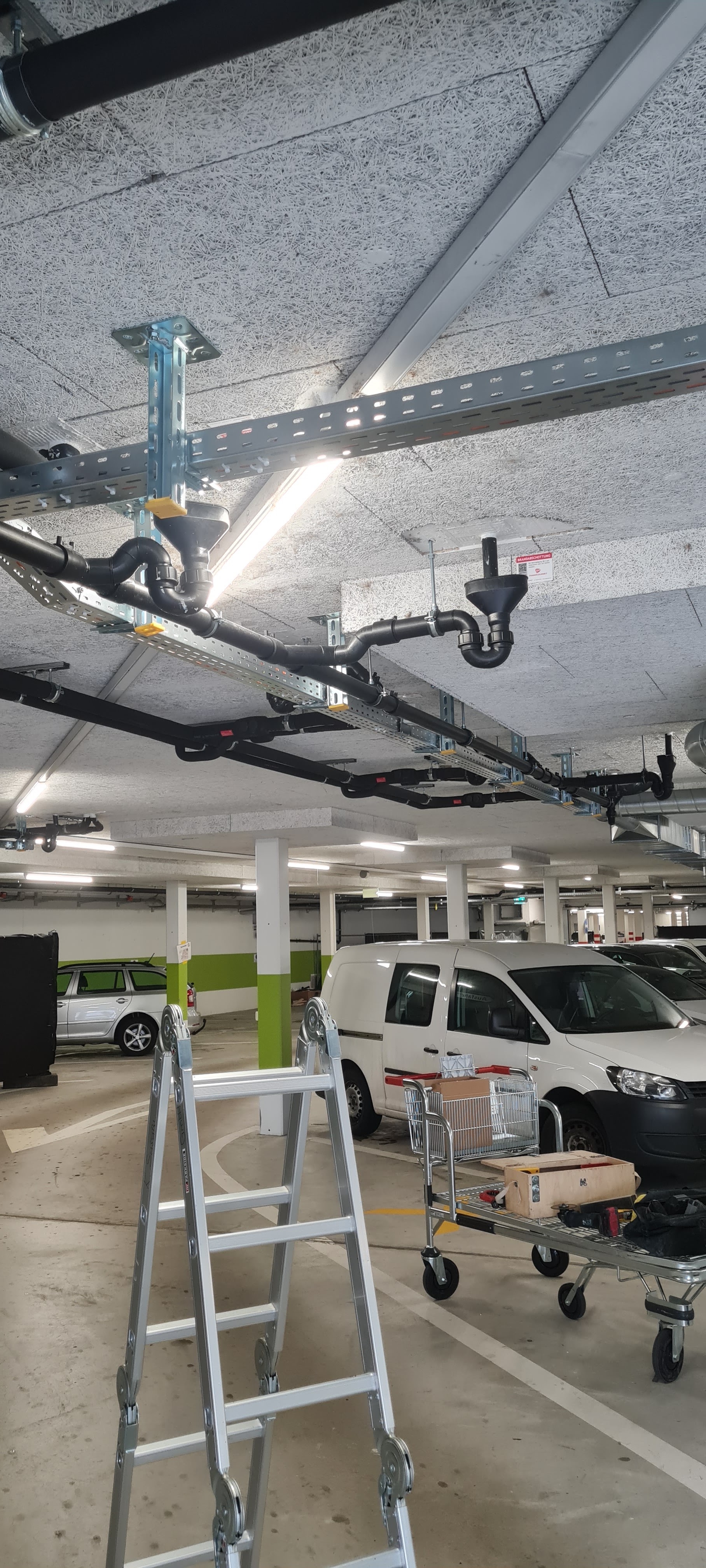Tiefgarage mit Deckenleitungen und Firmenbussen der Susuri Haustechnik GmbH
